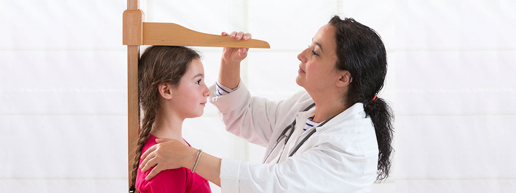 Image of nurse measuring height of young girl. Copyright: chassenet / 123RF Stock Photo