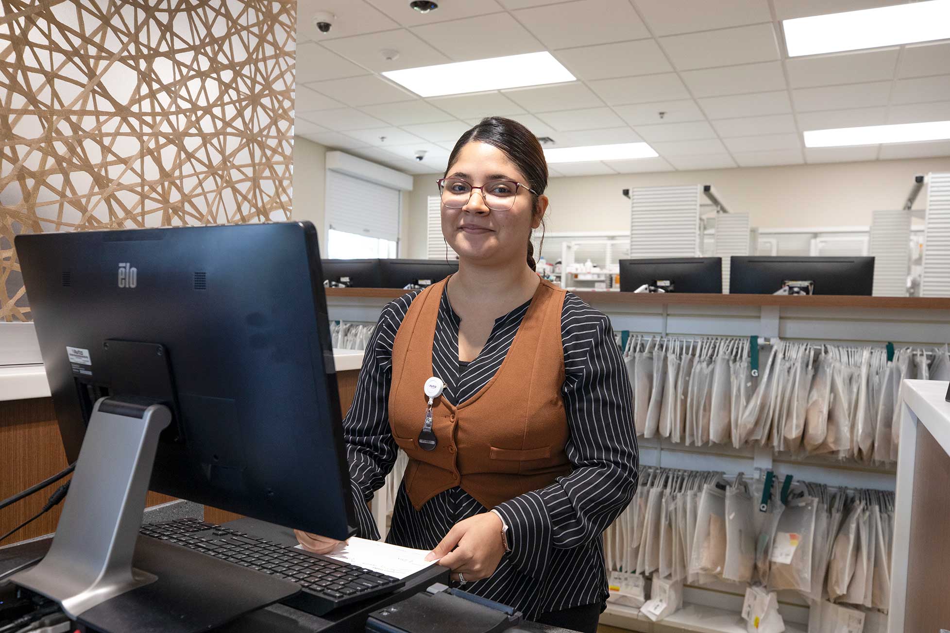 Avita Pharmacist stands behind counter ready to assist clients.